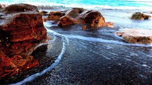 Una playa con rocas grandes y olas.