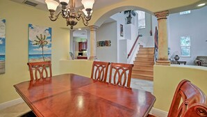 Un comedor con una gran mesa de madera, sillas, una araña y obras de arte en las paredes.