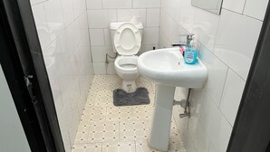 A small bathroom with a toilet, sink, and patterned floor tiles. - Beautiful Family House (Kampala)