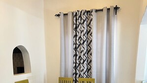 A dining area with a rectangular table and six chairs, a patterned curtain, and a tiled floor. - Beautiful Family House (Kampala)