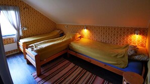 Une pièce avec deux lits en bois, un tapis à rayures et un papier peint à motifs.