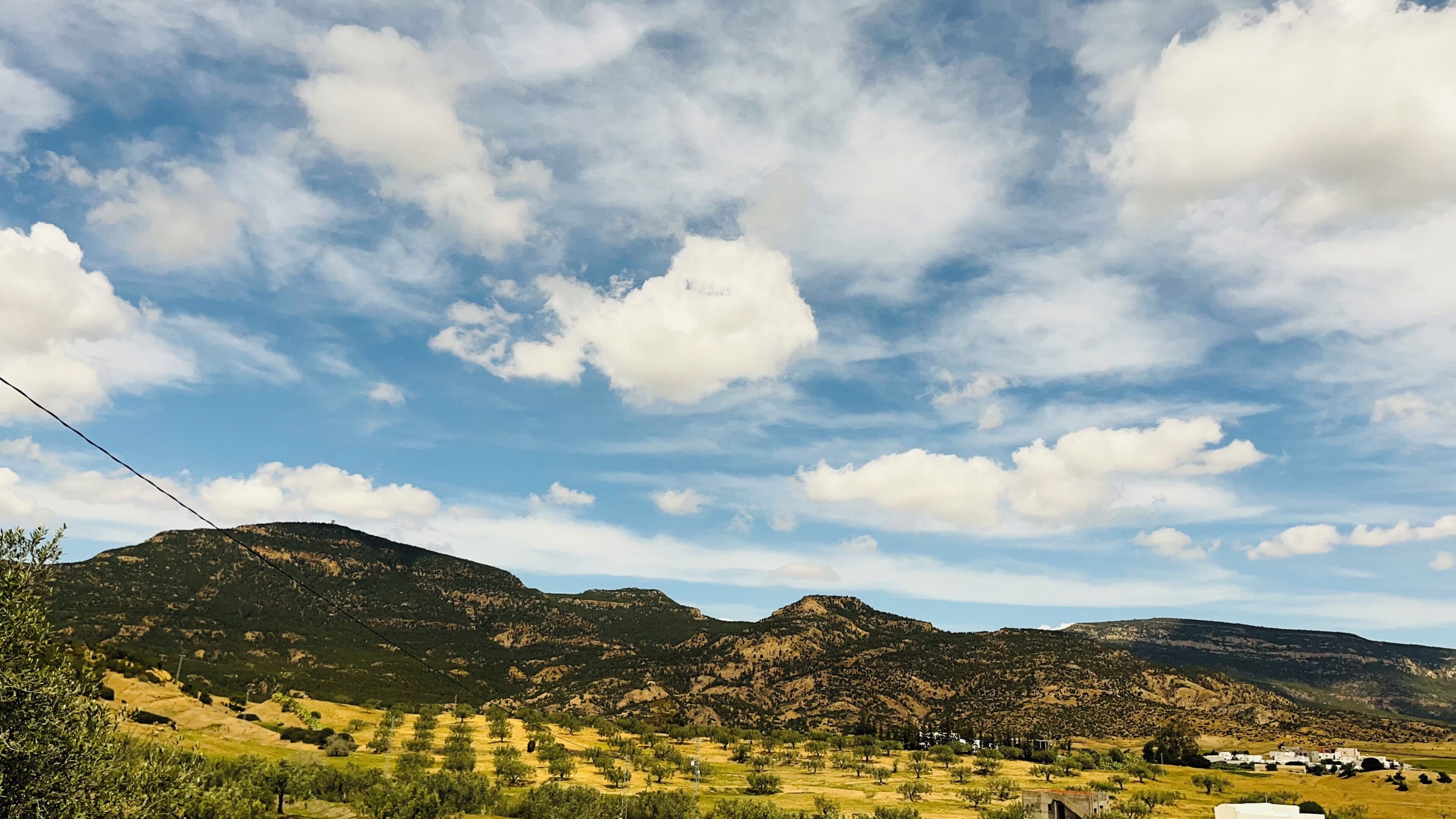 A mountainous landscape with a clear sky and scattered clouds.