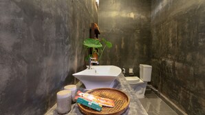 Een badkamer met een wit wastafelmeubel, een toilet en een kleine plant op de aanrecht.