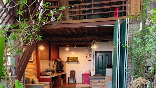 Een gezellig, rustiek interieur met een houten trap, een keukenhoek en zithoekjes.