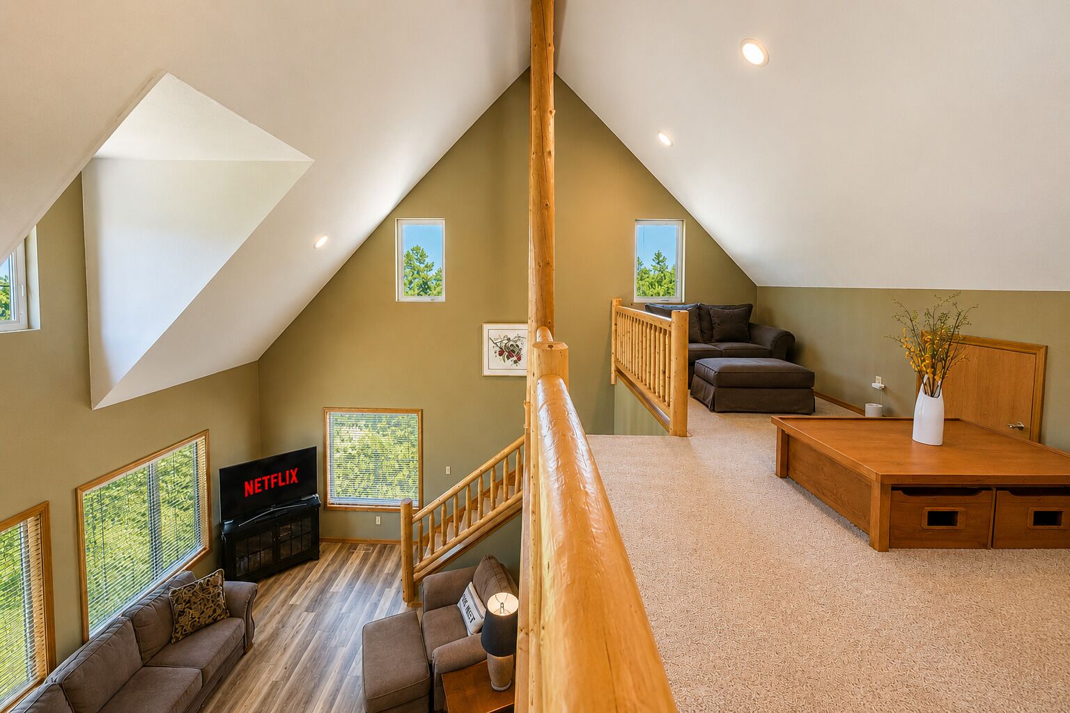 A loft-style room with a wooden staircase, a sofa, a TV, and a dining table.