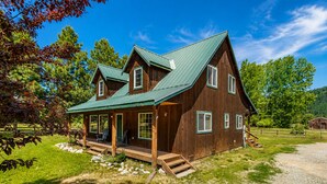 A wooden cabin with a porch, multiple windows, and a green roof. - Farmhouse In Plain 2 Bedroom Home by NW Comfy Cabins by RedAwning (Leavenworth)