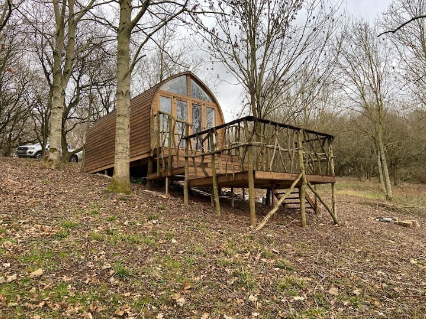 A wooden cabin with a glass front and a wooden deck.