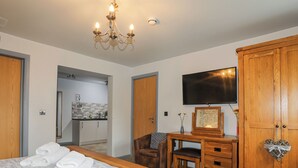 Une chambre d’hôtel comprenant un lit, un bureau avec une chaise, une armoire, une télévision et un lustre.
