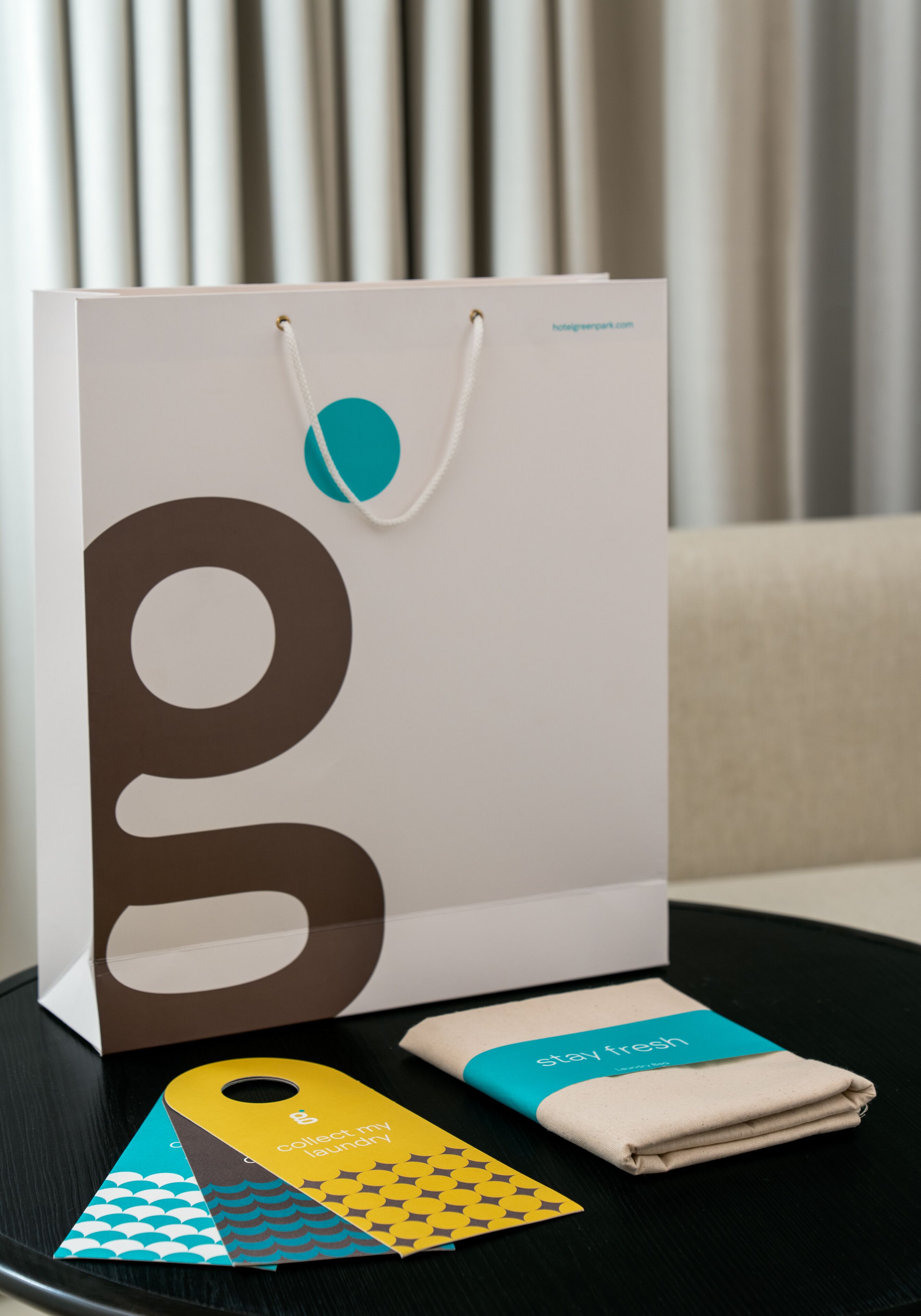 A white shopping bag with a teal and brown logo, a tag, and a folded towel on a black surface.
