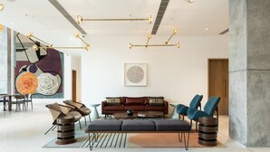 A modern living room with a sofa, chairs, a coffee table, and a unique floor lamp. - Greenpark Bengaluru (Bengaluru)