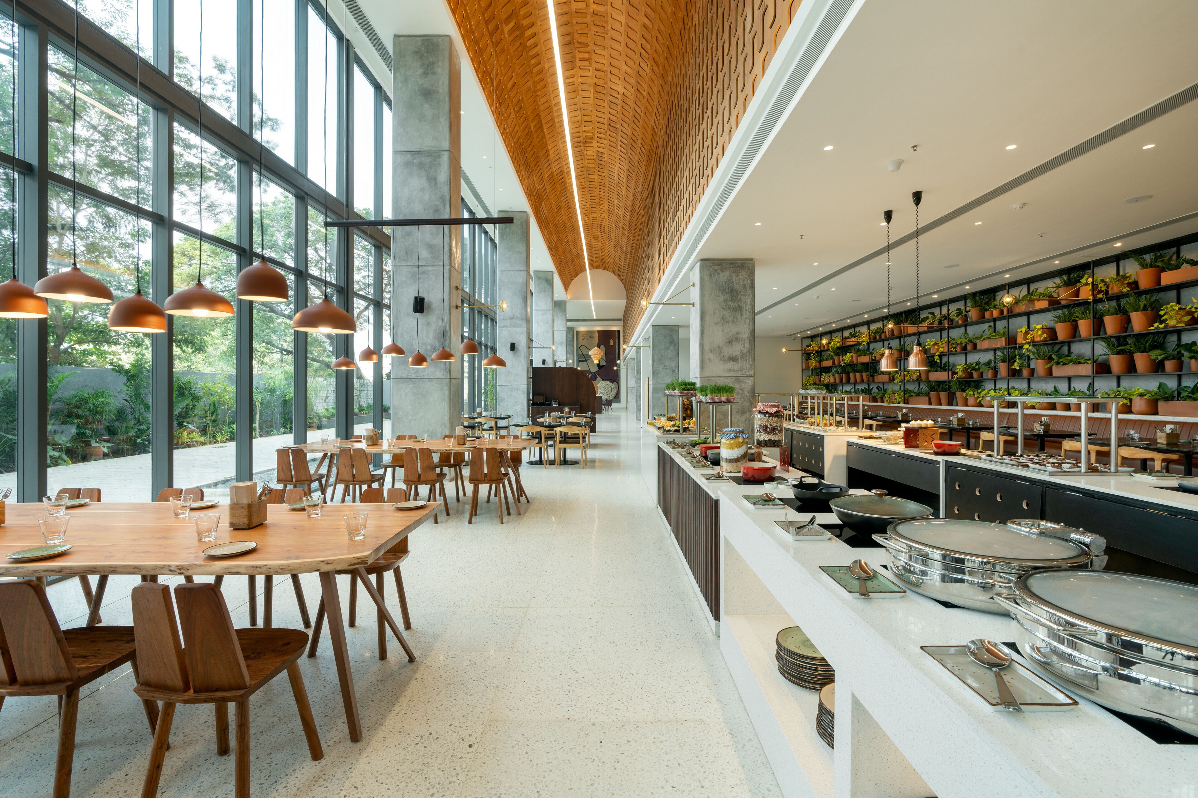 Een ruim restaurant in moderne stijl, met hoge plafonds, grote ramen en diverse zithoeken.