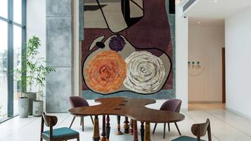 A modern dining area with a large abstract painting, a wooden dining table, and chairs.