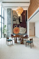 A modern dining area with a large abstract painting, a wooden dining table, and chairs.