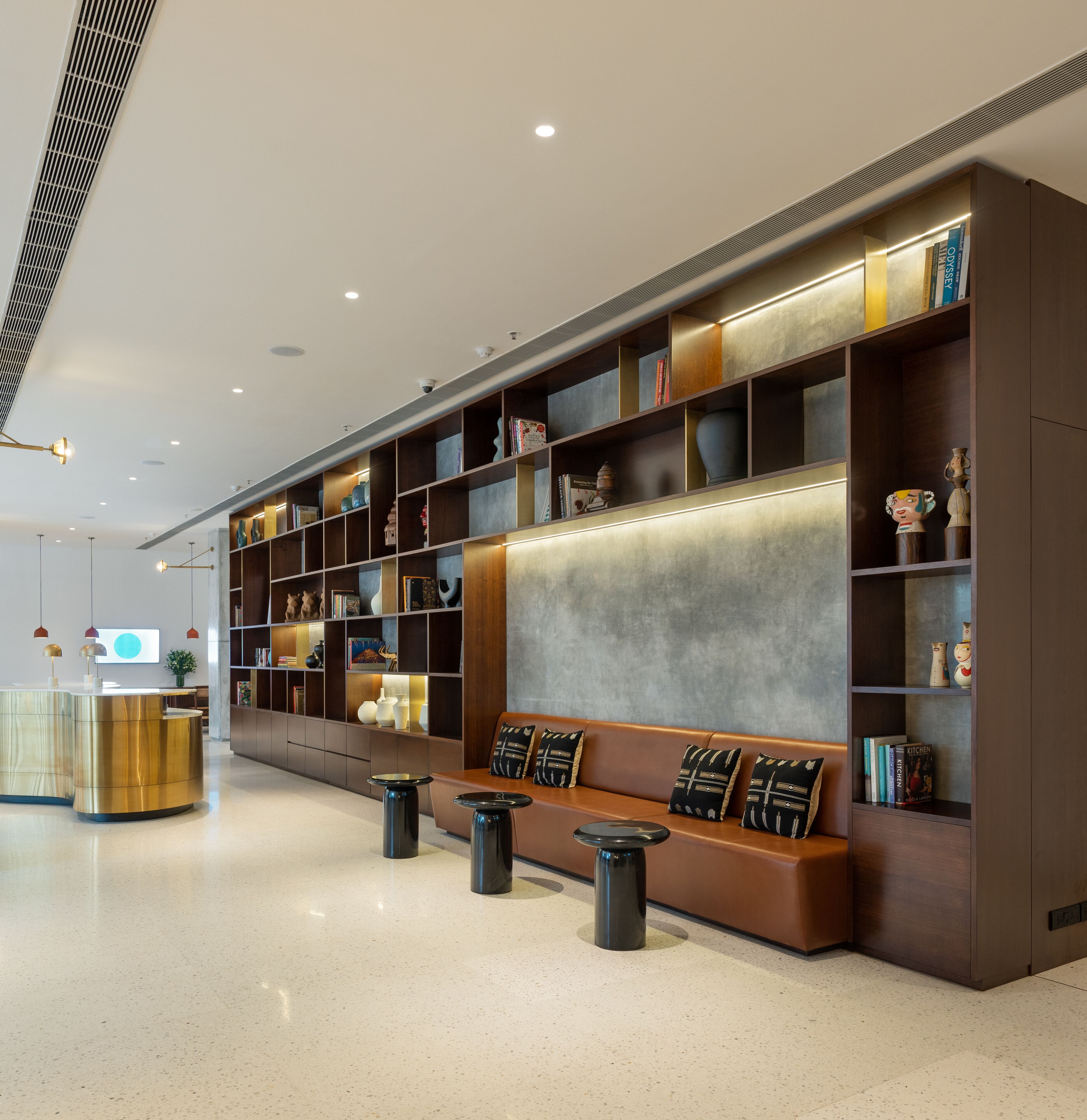 A modern reception area with a reception desk, seating area, and a large bookshelf filled with books and decorative items.