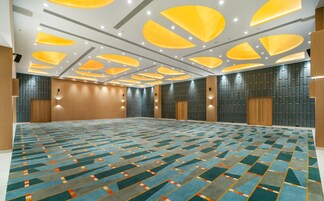 A large, well-lit conference room with a patterned carpet, recessed ceiling lights, and wooden panel walls.