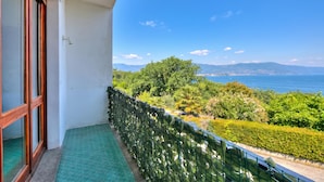 A balcony with a view of the sea and mountains, a green patterned floor, and a metal railing. - La Finestra Sul Lago: Lake Maggiore View & Garden (Stresa)