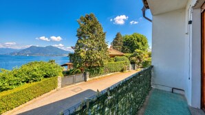 A balcony with a view of the sea, a mountain, and a well-maintained garden. - La Finestra Sul Lago: Lake Maggiore View & Garden (Stresa)