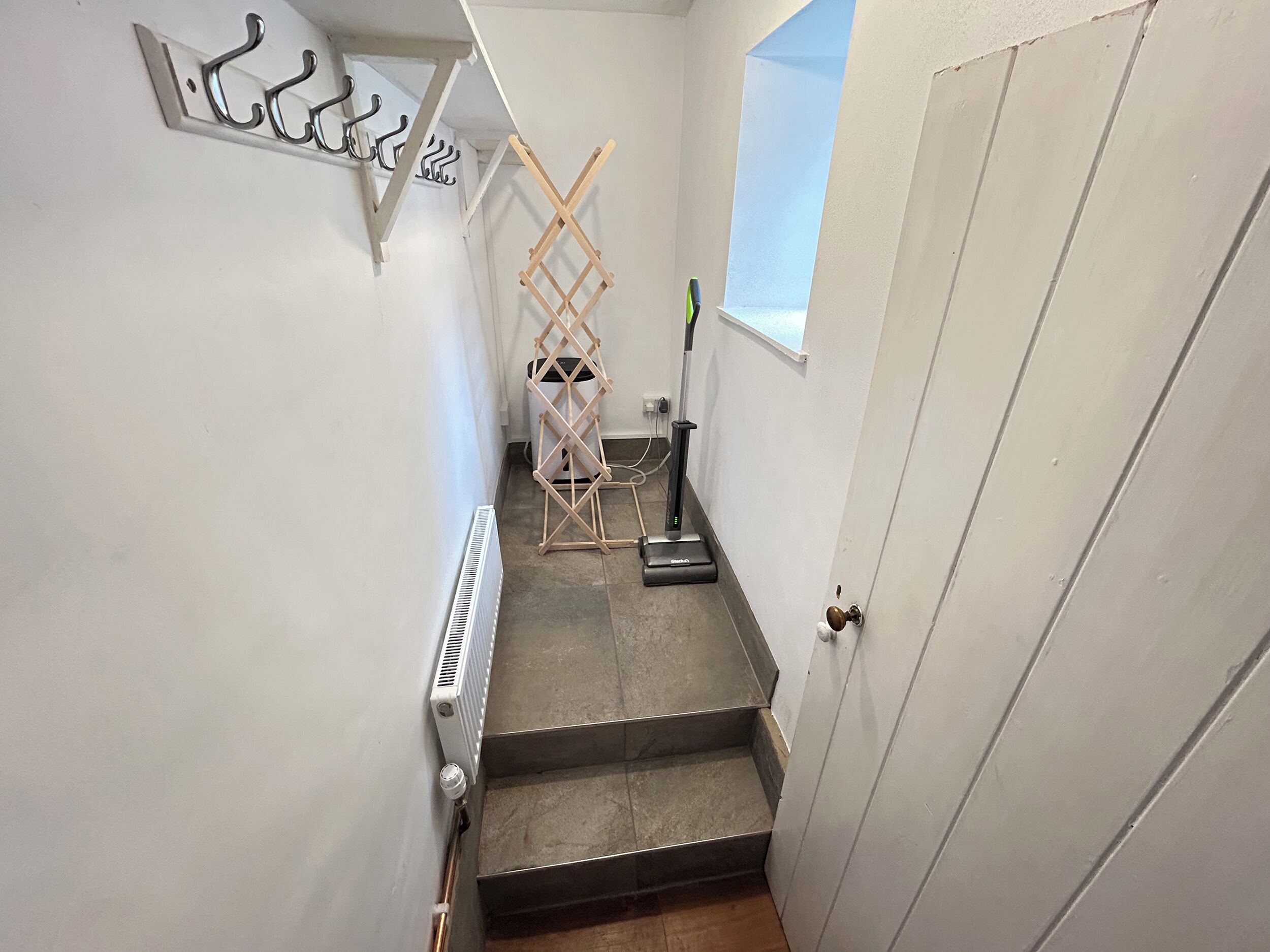 A narrow stairway with a radiator, a drying rack, and a vacuum cleaner.