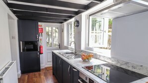 A modern kitchen with dark cabinetry, a marble countertop, and a built-in oven.