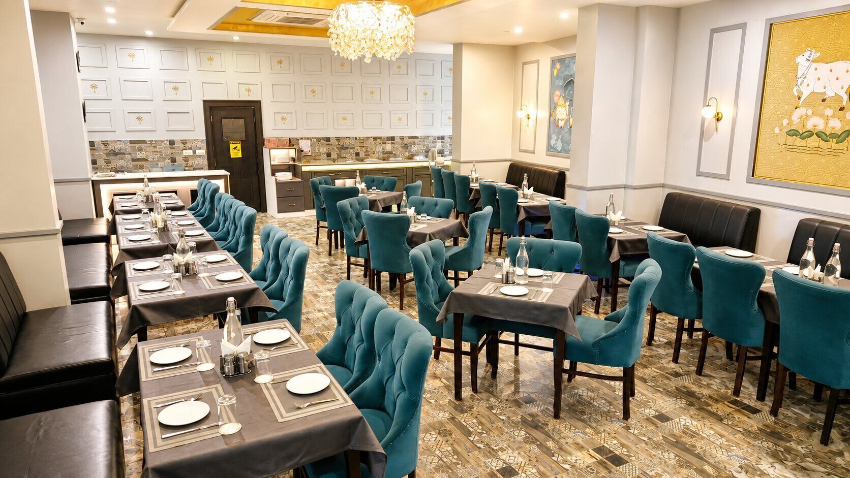 A restaurant with multiple tables and chairs, a kitchen area, and a patterned floor.