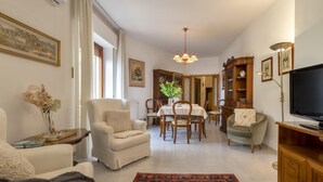 A living room with a dining area, a television, and a bookshelf. - Sardiniare - Catalogna 62 (Alghero)
