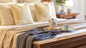 A neatly made bed with a patterned bedspread, a bedside table with a lamp, a pitcher, a cup, and a tray with a starfish. - Sardiniare - Catalogna 62 (Alghero)