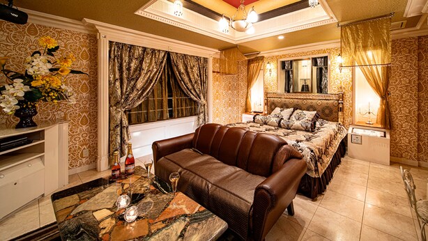 Une chambre élégamment aménagée, dotée d’un grand lit, d’un canapé en cuir et d’une table basse en marbre.