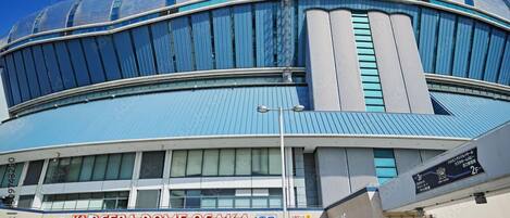 A modern building with a curved facade and large windows, labeled "Kydcera Dome Osaka".