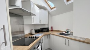 Een kleine keuken met een fornuis, magnetron, broodrooster en spoelbak.