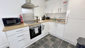 Una cocina moderna con armarios blancos, una campana extractora de acero inoxidable, un microondas y un horno empotrado.