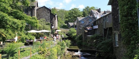 A narrow waterway flanked by stone buildings with outdoor seating areas and a sign for 'The Green Cafe'.