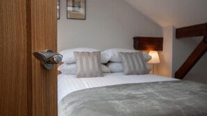 Une chambre à coucher avec un lit, des oreillers, une lampe de chevet et une porte en bois.