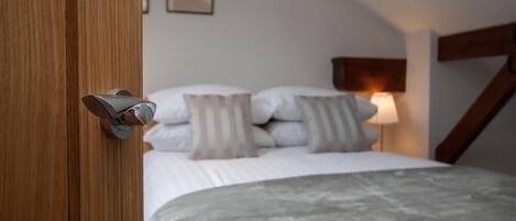 Une chambre à coucher avec un lit, des oreillers, une lampe de chevet et une porte en bois.