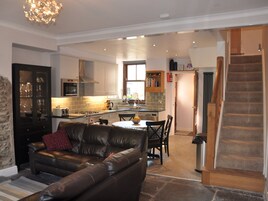 A modern living room with a leather sofa, a dining table, and a kitchen in the background.