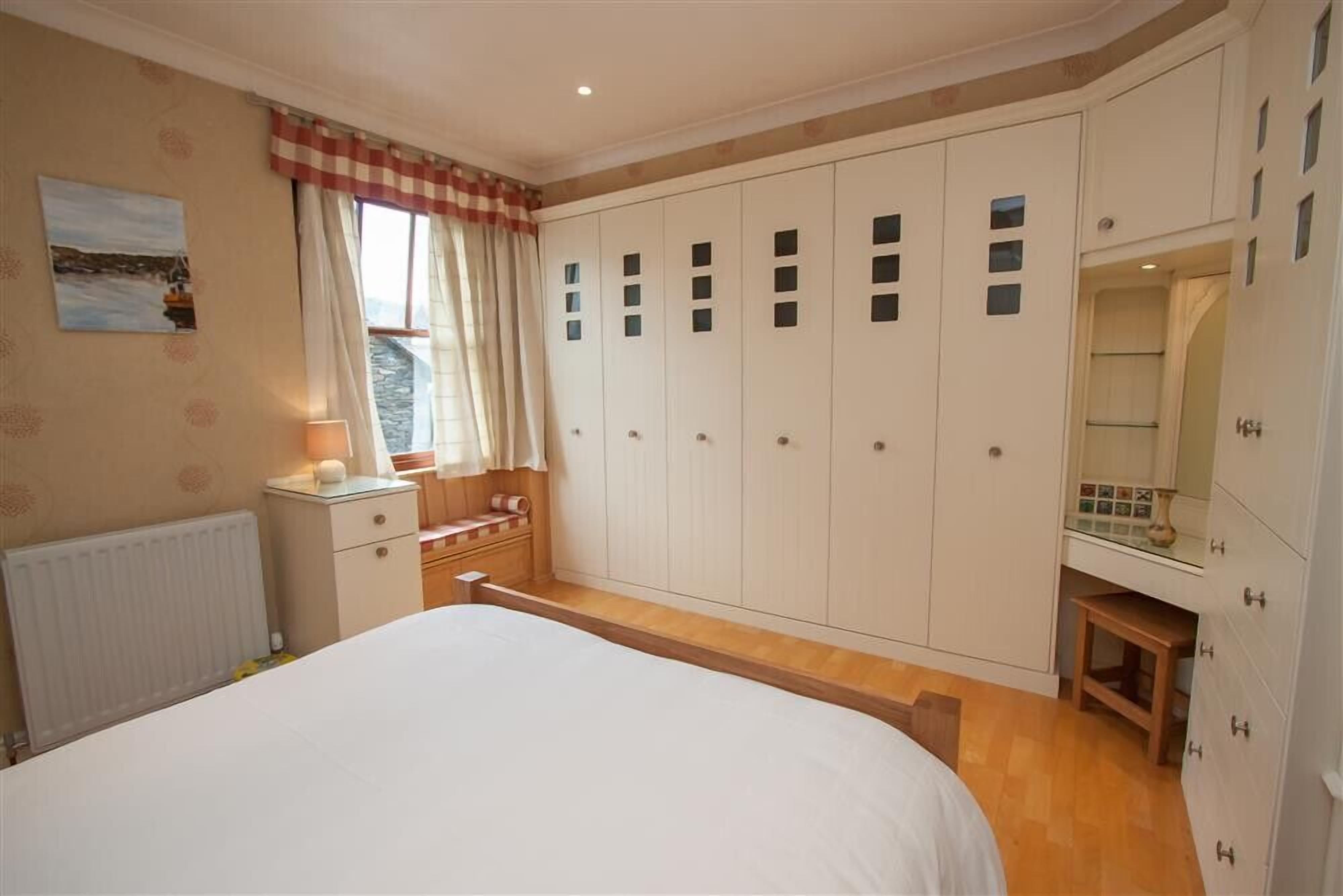 Ein Schlafzimmer mit einem großen Bett, einem Schminktisch, einem Kleiderschrank und einem Ankleidezimmer.