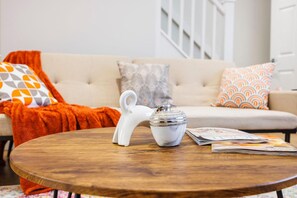 A round wooden table with a white ceramic teapot and a white ceramic sugar bowl.