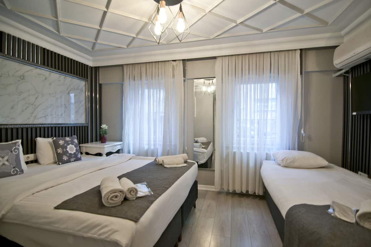 A hotel room with two beds, a large mirror, and a ceiling with a geometric design.
