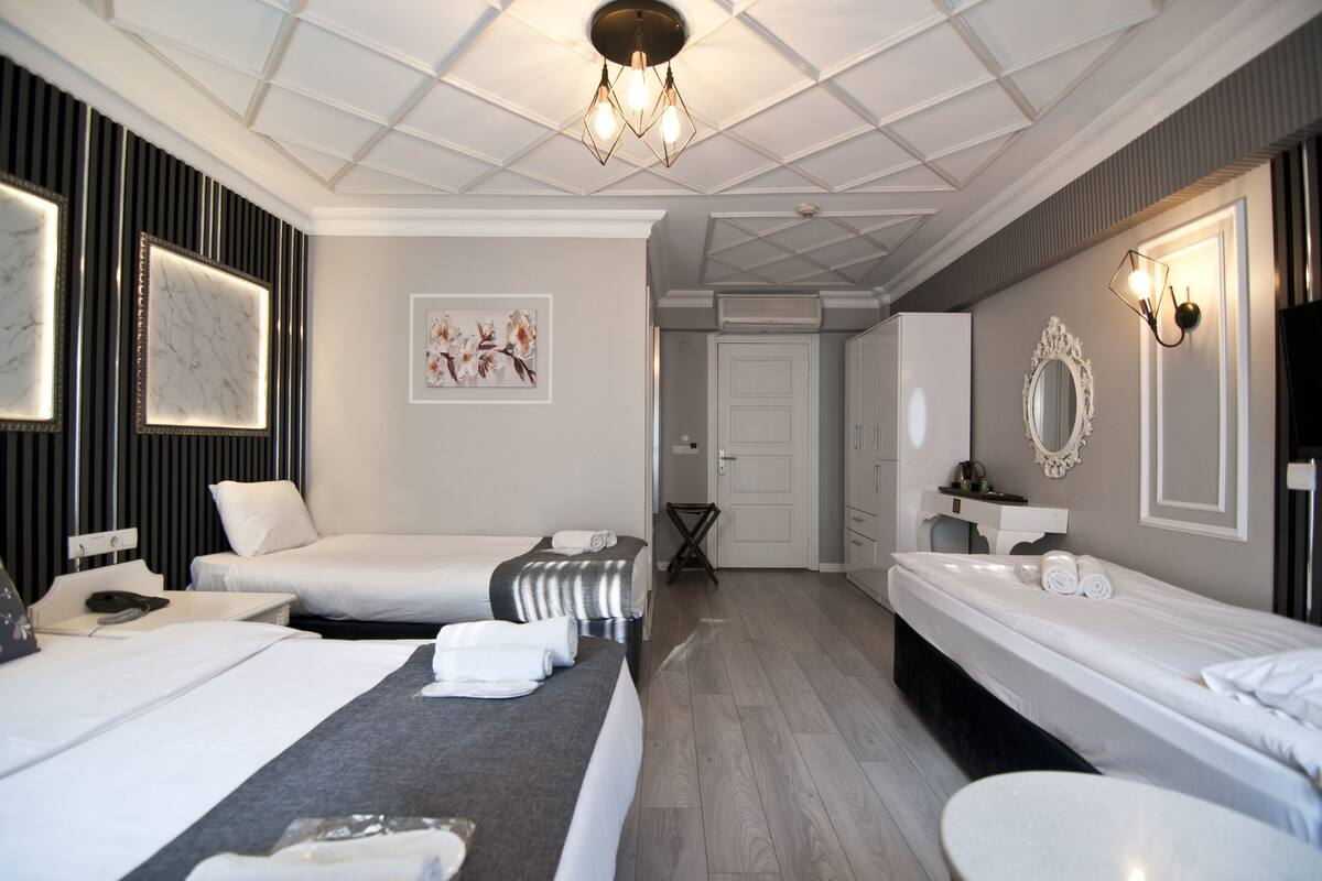 A hotel room with two beds, a bathroom, and a dining area.