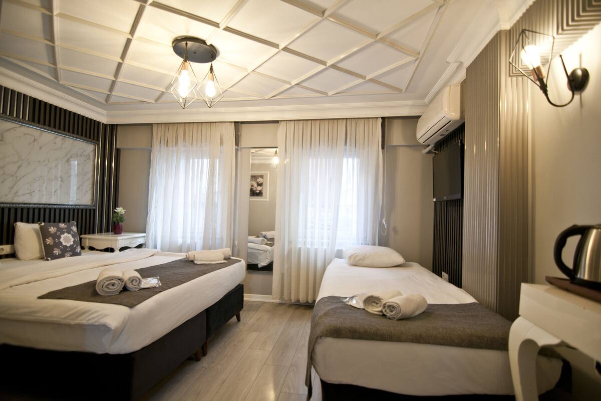 A hotel room with two beds, a large mirror, a flat-screen TV, and a coffee maker.