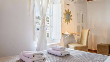 Une chambre d’hôtel avec un lit, une chaise, une petite table et une fenêtre avec des rideaux.