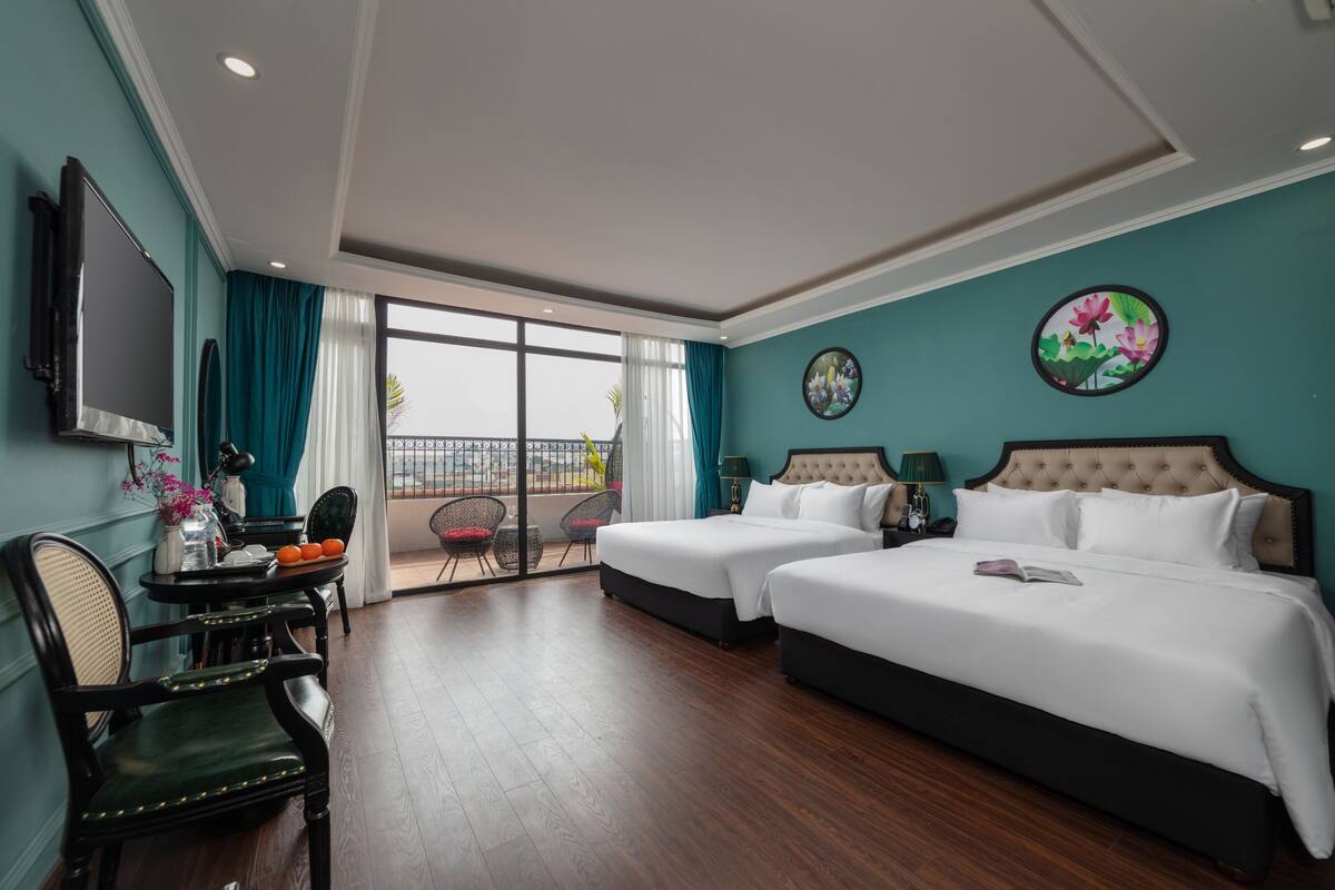 Een hotelkamer met twee bedden, een televisie, een eettafel met stoelen en een balkon met uitzicht.