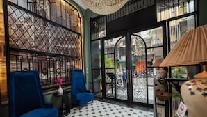 A lobby with two blue armchairs, a patterned floor, and a view through a glass door.