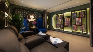 A massage room with a massage table, a blue chair, and a wall with framed artwork.