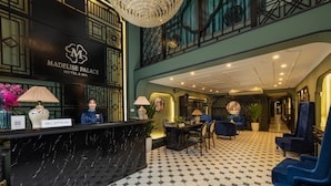 A reception area with a black marble counter, a reception desk, and a seating area with blue upholstered chairs.