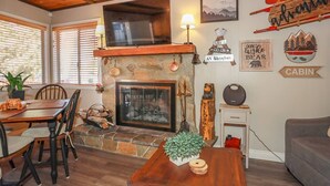 Un intérieur de chalet chaleureux, avec une cheminée en pierre, des meubles en bois et une décoration rustique.