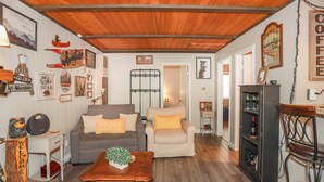 Un salon chaleureux avec un plafond en bois, deux canapés, une table basse et divers éléments de décoration murale.
