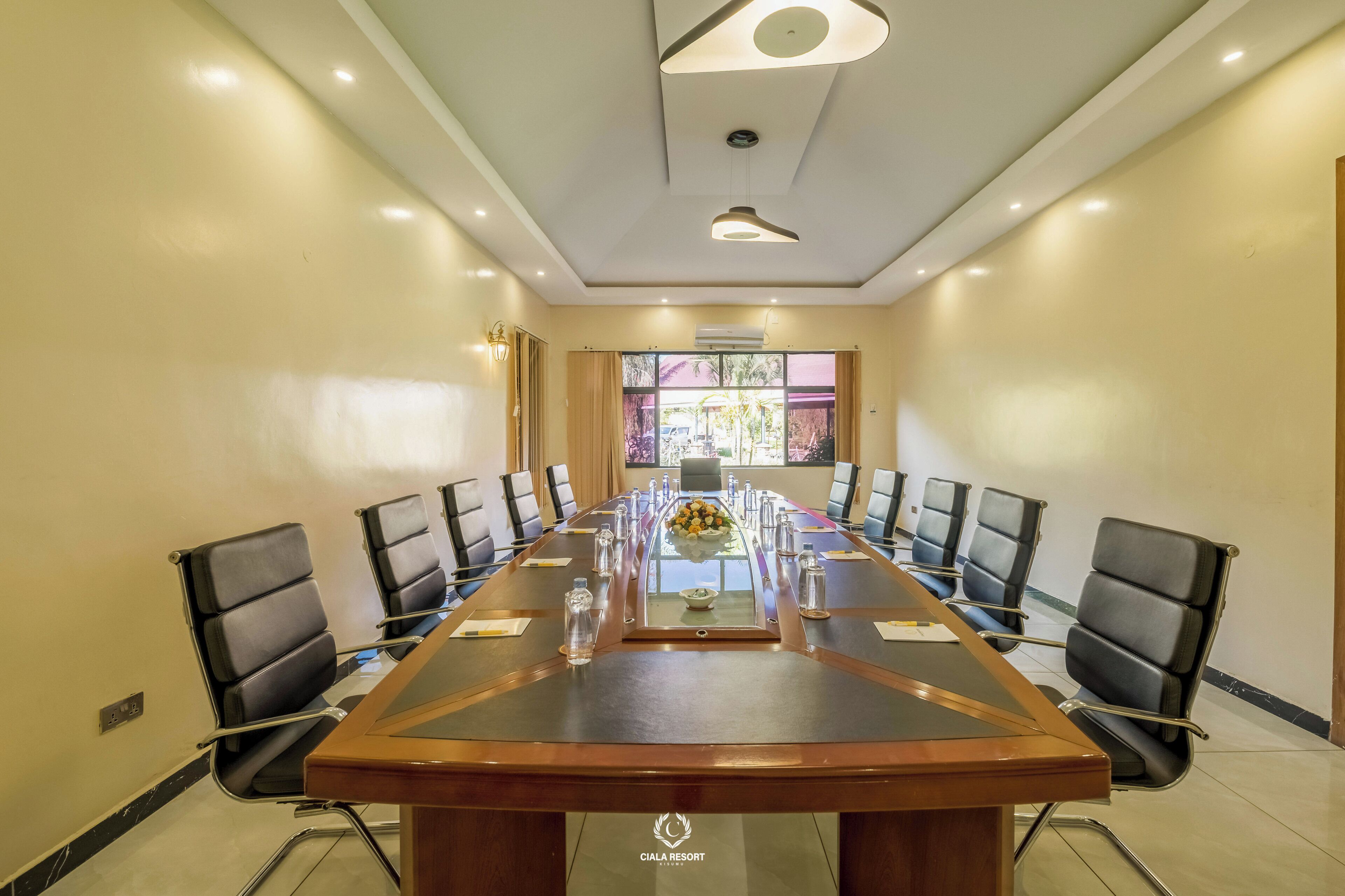 A conference room with a long table, black chairs, and a glass partition.