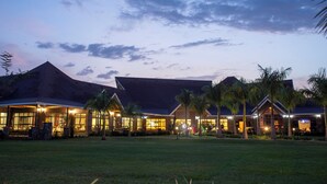 A hotel with a large lawn, palm trees, and a well-lit entrance. - Ciala Resort Best Hotel in Kisumu Kenya (Kisumu)