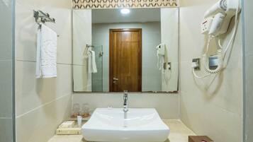 A bathroom with a large mirror, a sink, a hairdryer, and a towel rack.