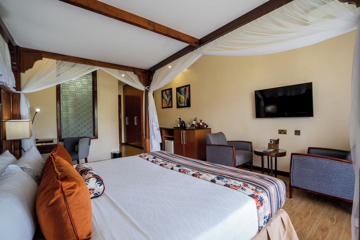 Ein Hotelzimmer mit einem großen Bett, einem Schreibtisch, einem Sessel, einem Fernseher und einem kleinen Tisch.